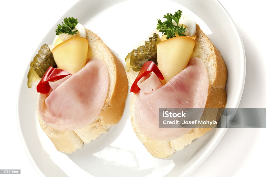 Open sandwiches with ham and egg Two open faced sandwiches with ham, egg, cheese, cucumber and pepper on plate. Decorated with parsley, white background, selective focus, shallow DOF. Appetizer Stock Photo