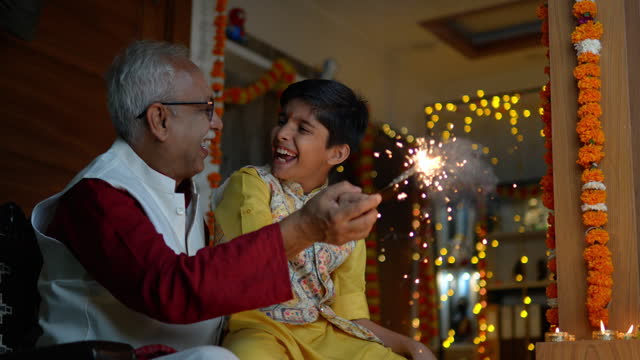 Grandfather and grandson playing with sparkler at home