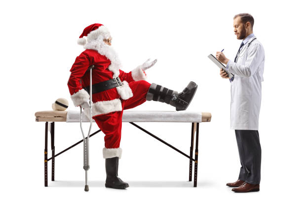 père noël avec une jambe blessée parlant à un médecin masculin et assis sur une table de thérapie - christmas crutch holiday christmas decoration photos et images de collection