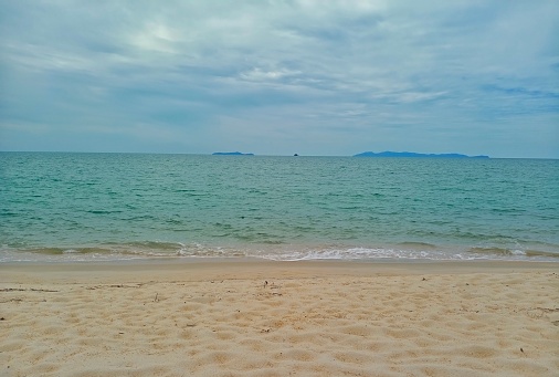 Beautiful sandy beach with white sand and rolling calm wave on sunny day