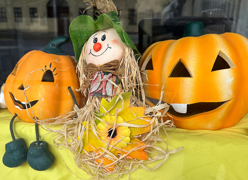 Vernon, BC, Canada- September 28,2022:  Front porch of old log cabin with Autumn arrangement of pumpkins,chrysanthemums, and straw man.  Partial door and window. Log structure.