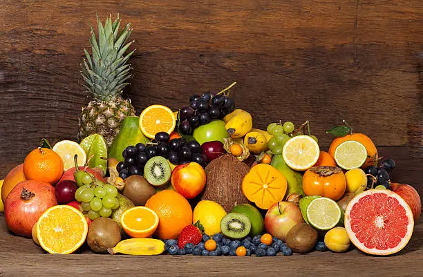 Many different tropical fruits in front of a wooden background
