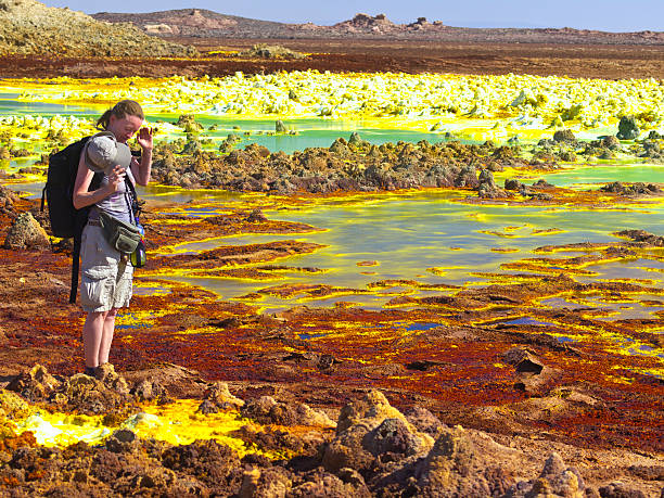 Tourist at Dallol Tourist woman, watching  fragile Dallol crust as part of Volcanic remains after 1926 eruption of Dallol volcano. It is like Hot Springs with geothermal and volcanic activity with characteristic white, yellow and red colours from  sulphur and potassium salts coloured by various ions. It is located in the Danakil Depression with the highest average temperatures on the planet and is considered the most remote and beautiful place on Earth, North East Ethiopia near Eritrea in Africa. 1926 stock pictures, royalty-free photos & images