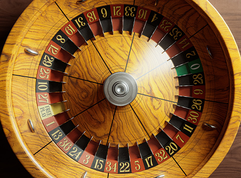 A closeup of a vintage antique roulette wheel with red and black markers with an ornate base on an isolated background - 3D render