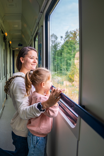Family traveling in a train and looking through window. Woman with child traveling by railway in Europe. High quality photo