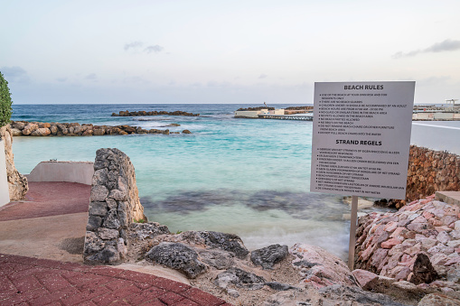 A sign of instructions on a rocky shoreline of a beach on a tropical island.