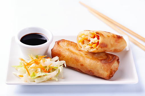 High angle view of vegetable spring roll with soy sauce on white background