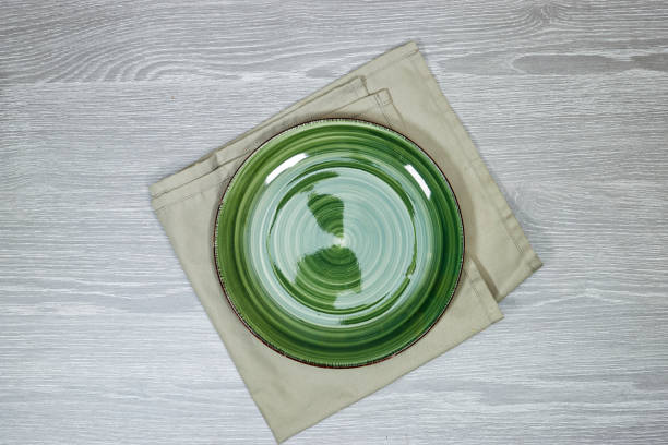 istock empty round green plate on tablecloth for food on wood table. Empty dish on napkin with space for your design 1759272246