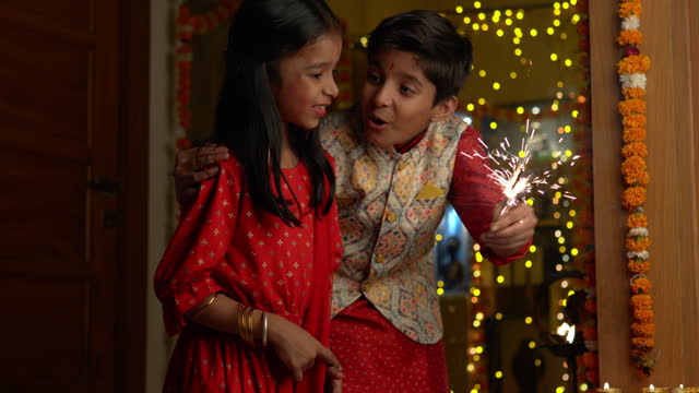 Happy siblings playing with sparklers at home during Diwali
