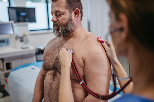 Overweight patient having problem with breathing, doctor using stethoscope to examine symptoms for asthma. Obesity affecting middle-aged men's health. Concept of health risks of overwight and obesity.
