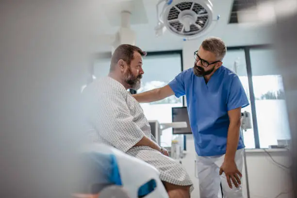 Photo of Supportive doctor soothing a worried overweight patient, discussing test result in emergency room. Illnesses and diseases in middle-aged men's health. Compassionate physician supporting stressed patient. Concept of health risks of overwight and obesity.