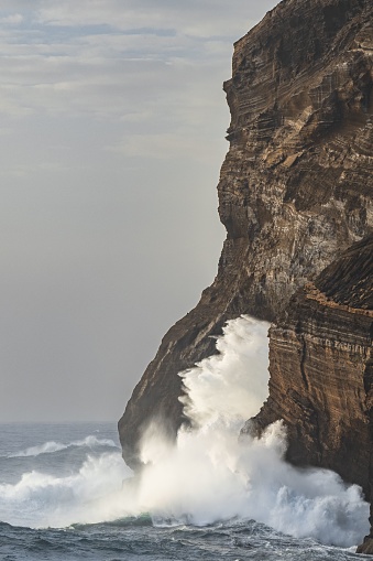 A dramatic scene of powerful waves crashing against a rocky shoreline along the coastal ocean