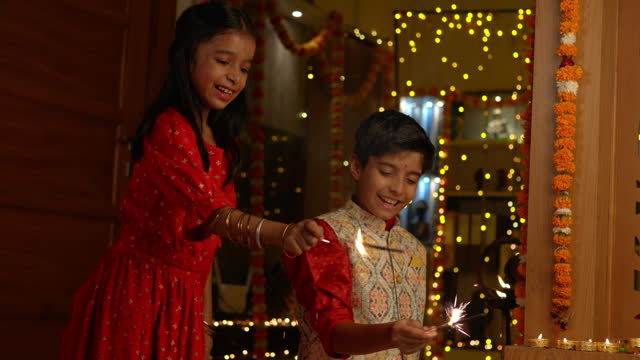 Happy siblings playing with sparklers at home during Diwali