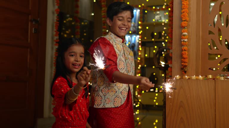 Happy siblings playing with sparklers at home during Diwali