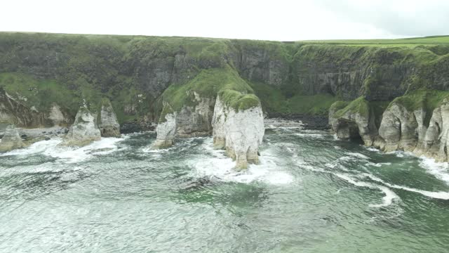White Limestone Cliffs With Arches On The Coast Of Antrim In Portrush, Northern Ireland. aerial sideways