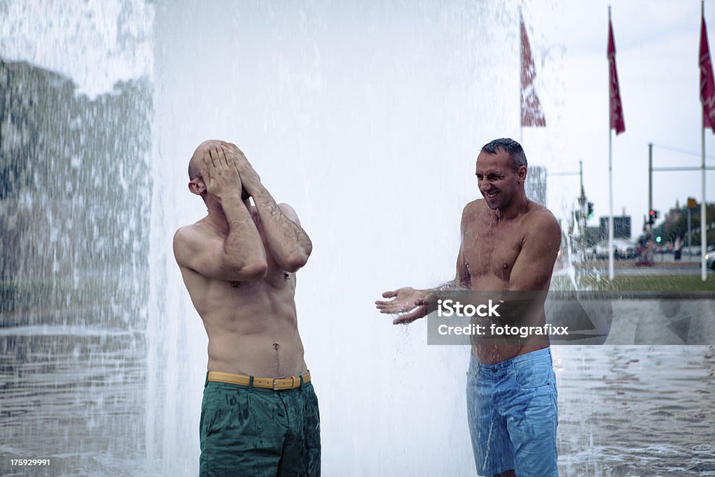 Deux hommes de prendre un rafraîchissement dans une fontaine - Photo de Adulte libre de droits