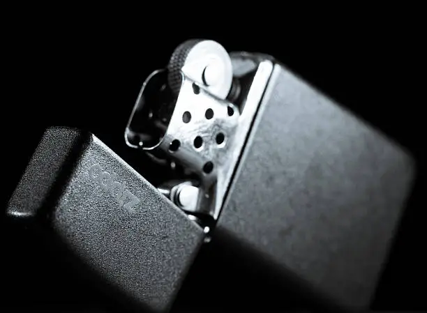 A black zippo lighter lying in open position isolated on black background.