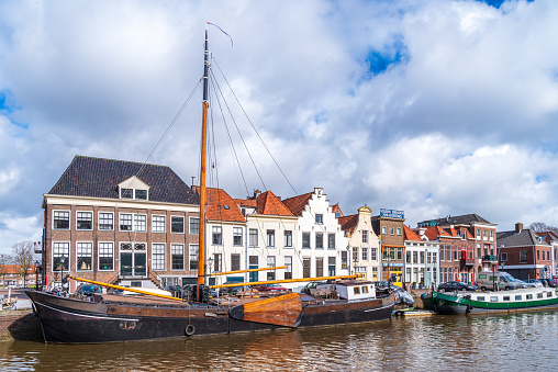 Zwolle, Netherlands - March 14, 2021: Old boats and barges in front of some nice gabled houses in the dutch city of Zwolle