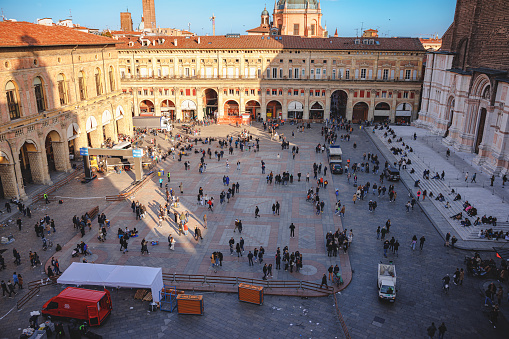 Bologna, Italy - March 5, 2023: High angle view on the stone paved square with tourists, historical buildings on Piazza Maggiore on a clear day in the center of Bologna, Italy