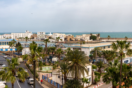 Alger, Algiers, Algeria, 04 19 2023 : panoramic view of the port and the Boulevard Amara Mohamed Rachid. Green palm trees, cars, Mediterranean sea, buildings.