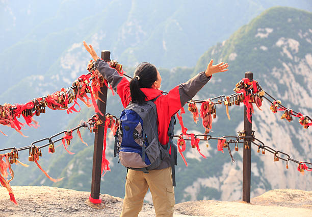Huashan, China -  August 2019 : Red and yellow ribbons attached to the protective barrier on a lookout with the stunning mountain landscape view from the summit of West Peak, Huashan mountain, Shaanxi Province