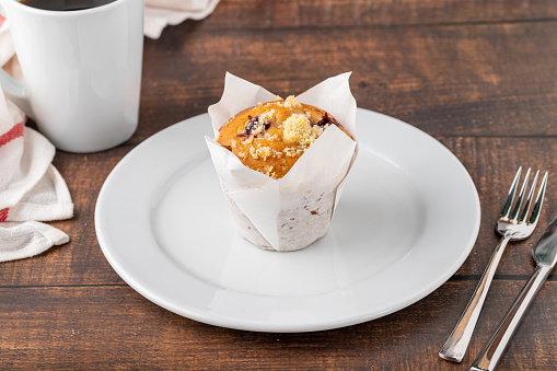 Vanilla and hazelnut muffin or cupcake with coffee on wooden table