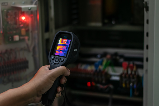 Professional Electrician use thermal infrared camera or thermometer scanning electrical system for preventive maintenance,Industrial thermography,Thermal image of power electric.