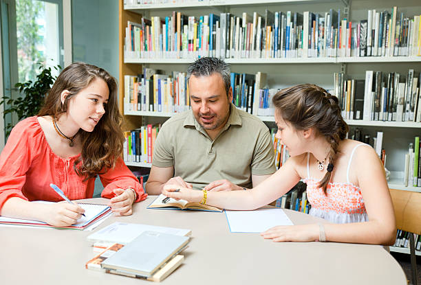 istock Father (or teacher) and daugthers at the public library. 175940649