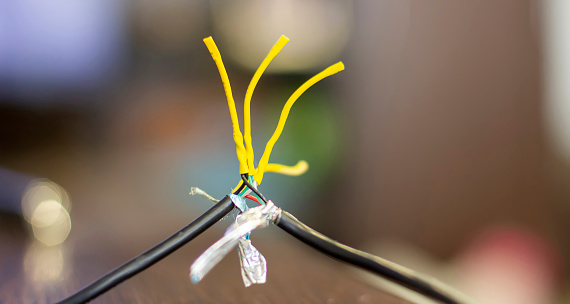 Close up of repaired wire with precise twists covered in heat shrink, showcasing the heat shrink protective and tidy finish. Yellow heat shrink for thin wires.