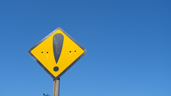 Yellow warning sign with copy space against blue sky background