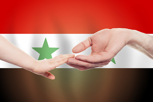 Syrian baby and parent hands on the background of flag of Syria Help, aid, support, charity concept