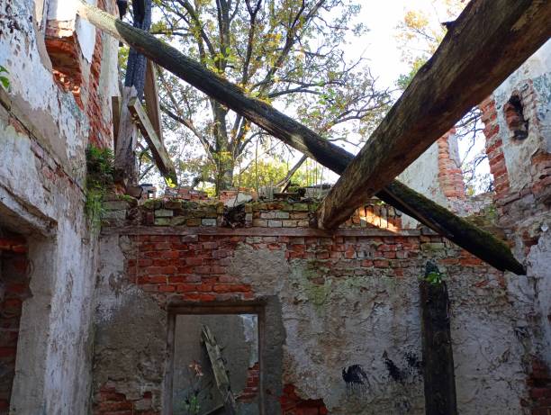 istock An old building destroyed by time and fire with brick walls and a missing roof. A house after a fire with burnt floor beams. 1759413111