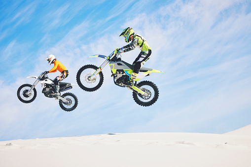 Jump, people and motorbike with exercise, competition and challenge with safety, fitness and performance. Athletes, sand and bikers with mockup, practice and cycling with freedom, workout and energy