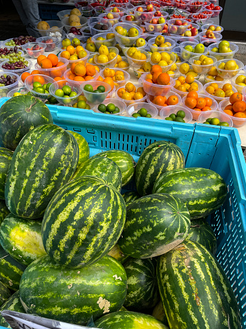 Stock photo showing fresh fruit and vegetables displayed in plastic bowls at green grocer's shop.  Limes, satsumas, oranges, lemons, green and red apples and white and black grapes have been pre-weighed to limit contact with customers.