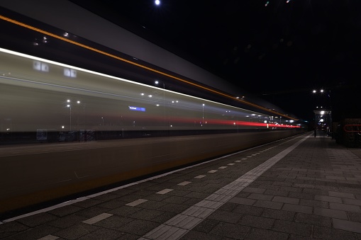 A dramatic night time shot of a train in motion with illuminated tracks under its wheels