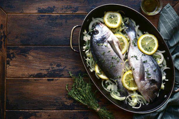 Raw fresh dorado prepared for baking with onion, lemon and thyme. Top view with copy space.