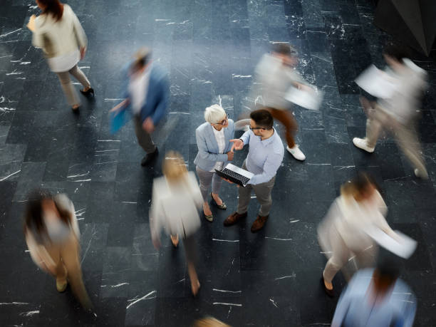 istock Above view of entrepreneurs talking while using laptop among colleagues in blurred motion. 1759435849
