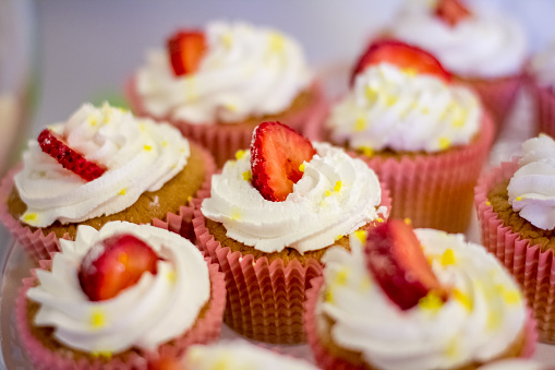 Cupcakes decorated with cream and strawberries on a white background.