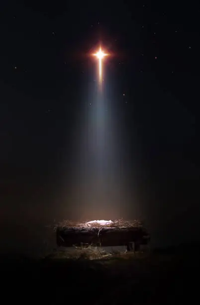 A bright and large star shines brightly, blessing baby Jesus in the manger of the stable. A background and concept that celebrates Christmas and suggests the birth and death of Jesus on the cross.