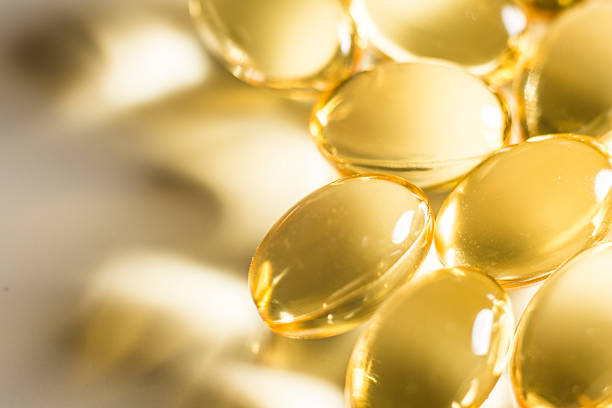 fischöl tablets makro glühend - cod liver oil fish oil vitamin e vitamin pill stock-fotos und bilder