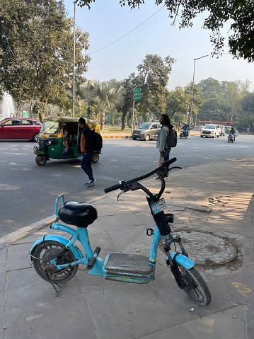 New Delhi, India - January 1, 2023: Stock photo showing close-up view City hire motor scooter parked in business, commercial and financial district of New Delhi, India. The hire bikes are part of a sharing system designed as an environmentally friendly initiative to help reduce city pollution.