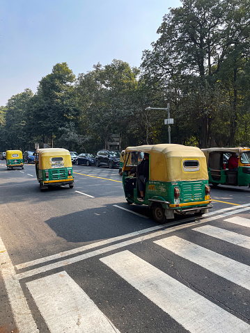 Connaught Place, New Delhi, India - January 1, 2023: Stock photo showing close-up, rear view of auto rickshaws transporting passengers around Connaught Place, one of the largest business, commercial and financial centres in New Delhi, India.