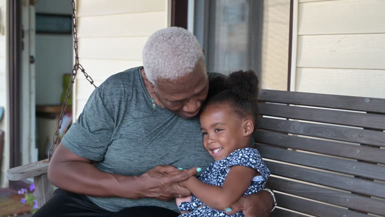 Playful grandmother and young granddaughter on front porch