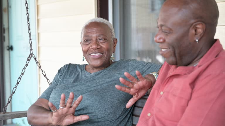 Smiling seniors sitting on porch swing and talking