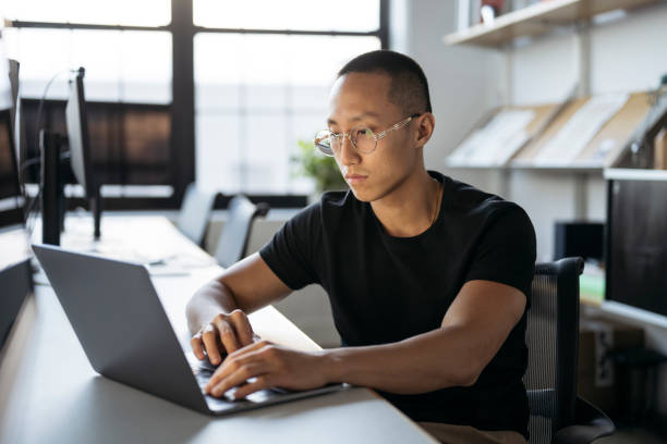 Focused young Chinese businessman using laptop