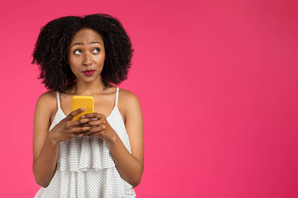 istock Thoughtful cheerful curly millennial african american lady with phone looking at empty space 1759484850