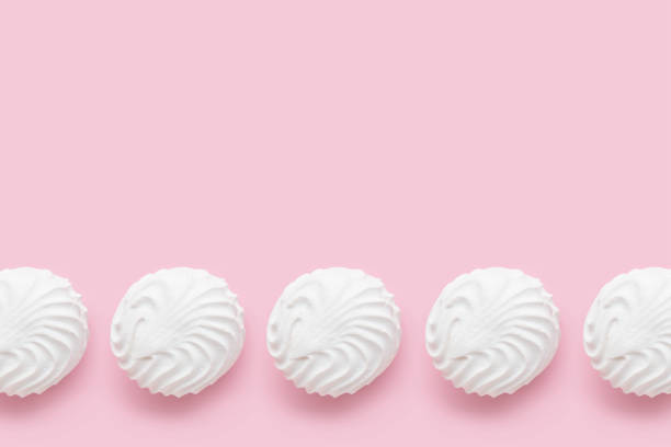 istock Soft white vanilla zephyr on light pink table. Pastel color. Banner with empty space for the text 1759487112