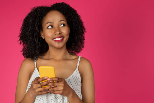 istock Positive pensive young black curly lady chatting at smartphone, looking at copy space 1759487133