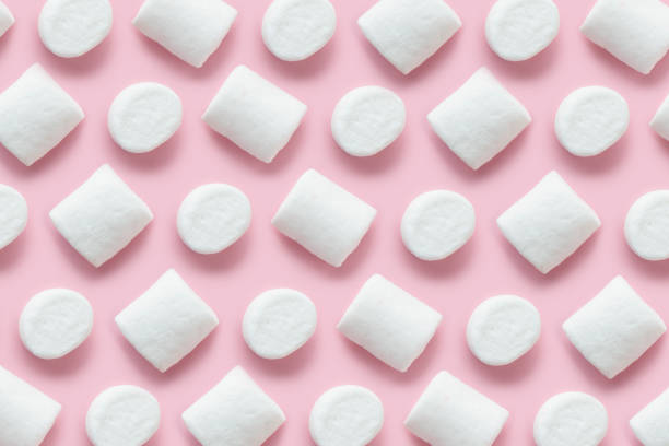 istock Rows of white marshmallows pattern on light pink table background in hard light. Pastel color 1759489372