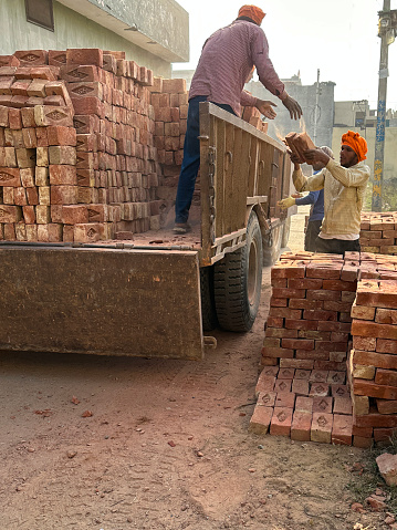 Bijnor, Uttar Pradesh, India - January 20, 2023: Stock photo showing a pile of handmade red bricks, which are pictured stacked up on the back of a lorry. These red clay bricks are part of an Indian building construction site.